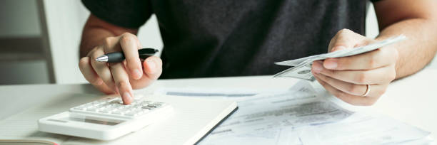Man use calculators and documents that calculate expenses in the home office. stock photo