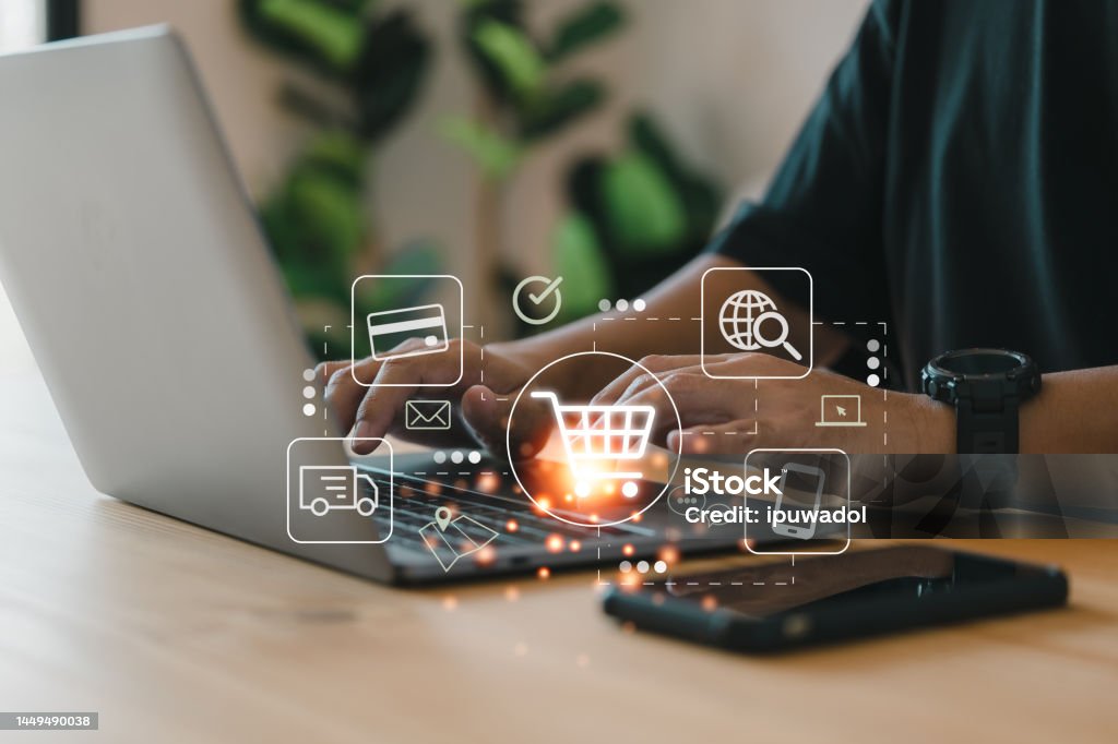 Online shopping and e-commerce technology concept, shopper using computer laptop to input order with trolley credit card delivery truck. E-commerce Stock Photo